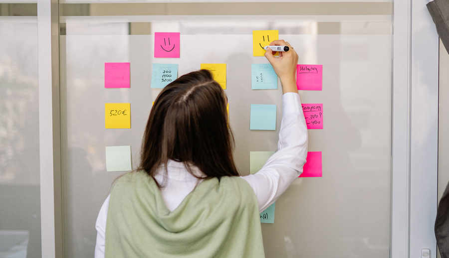 woman writing on sticky notes that are stacked on the wall