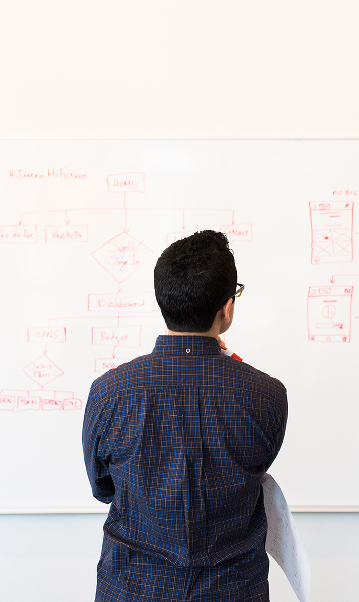 Man looking at dry erase board covered in diagrams